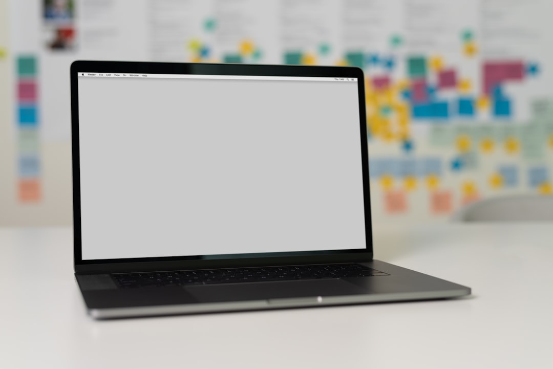 A laptop on a table with a blurred background of colorful sticky notes